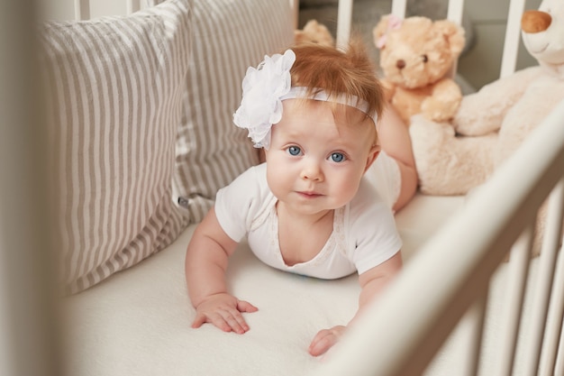 Baby girl in a crib with toys in the children's room