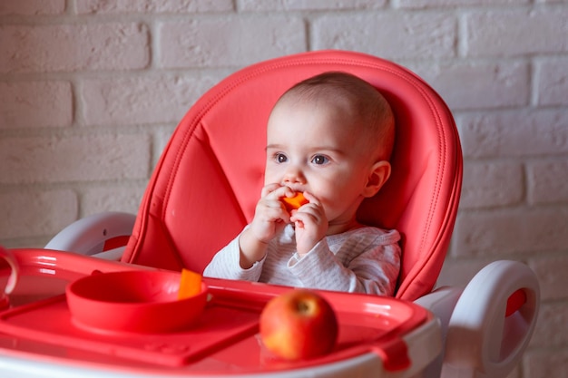 a baby girl is sitting on a children's high table at home in the kitchen