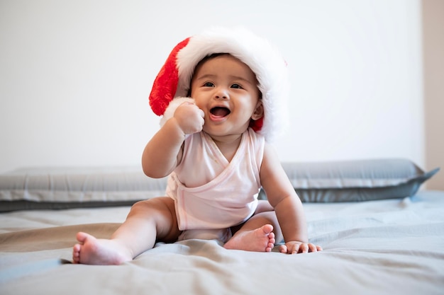 Baby girl laughing wearing santa claus hat at home