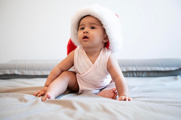 Baby girl laughing wearing santa claus hat at home