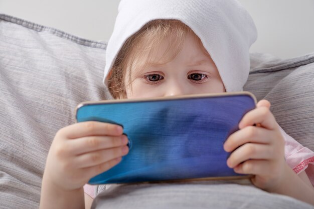 Baby girl playing with smartphone on the bed