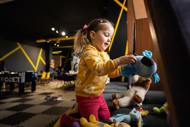 Baby girl playing with soft toys at modern kindergarten