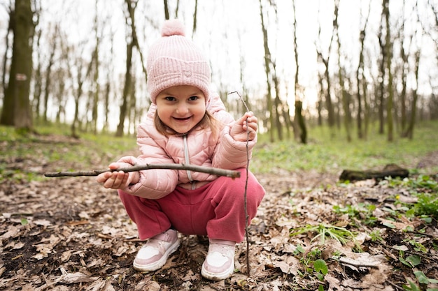 Baby girl playing with sticks in spring forest