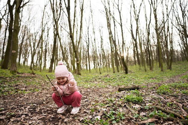 Baby girl playing with sticks in spring forest