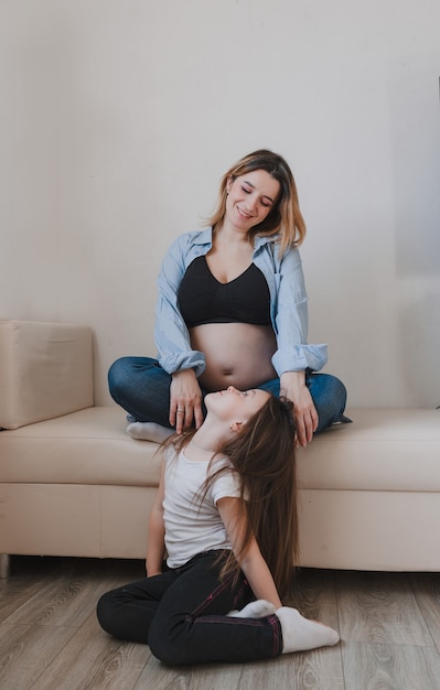 Baby girl and pregnant mother loving little sister next to mother's belly. happy family