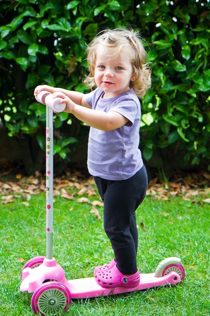 baby girl riding in the garden on scooter 