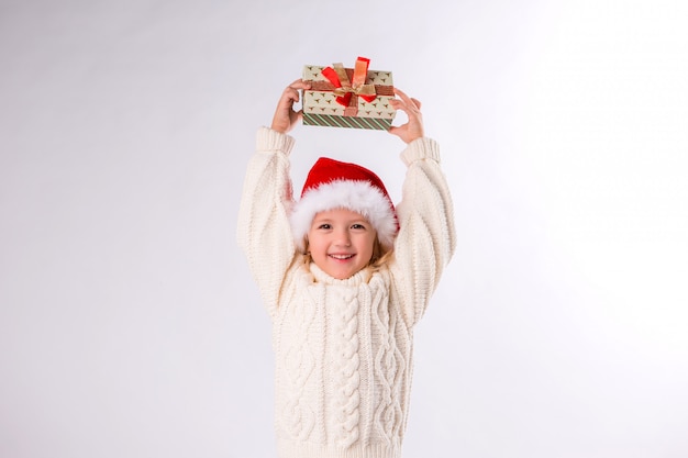 baby girl smiling in Santa hat holding gift box on white background