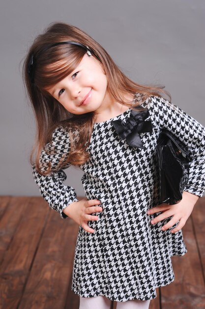 Baby girl standing on wooden floor over gray Wearing stylish dress