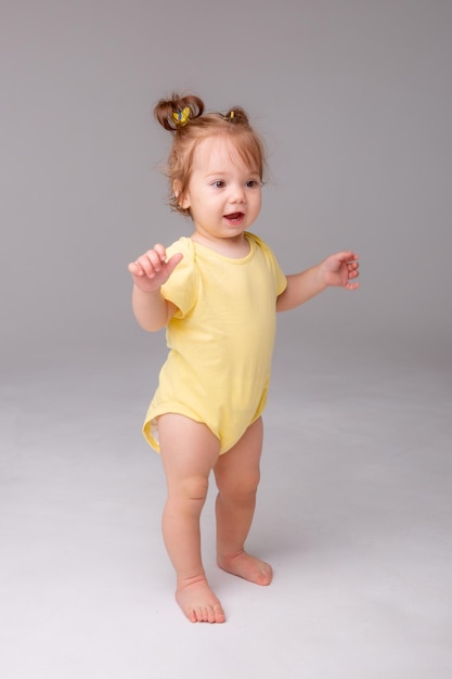 Baby girl starting to walk takes her first steps on a white background