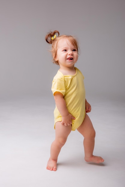 Baby girl starting to walk takes her first steps on a white background