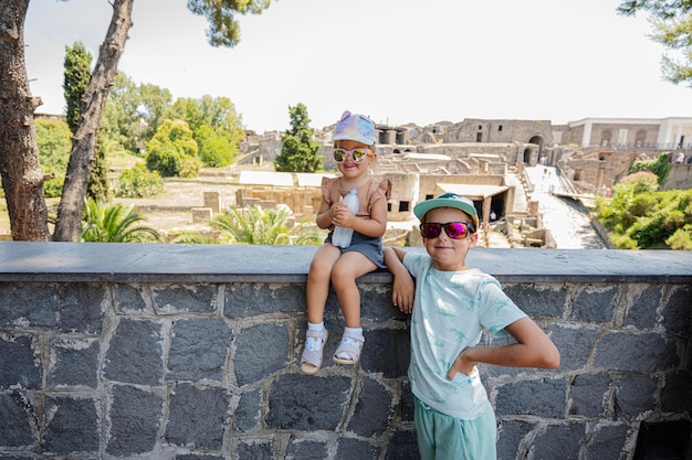 Baby girl tourist with brother against panoramic view of the ancient city of Pompeii