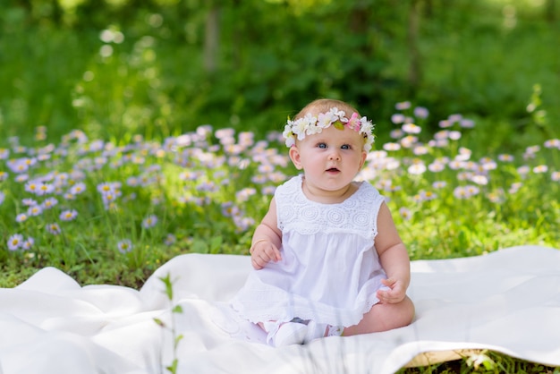 Baby girl in white dress in a spring garden with flowers