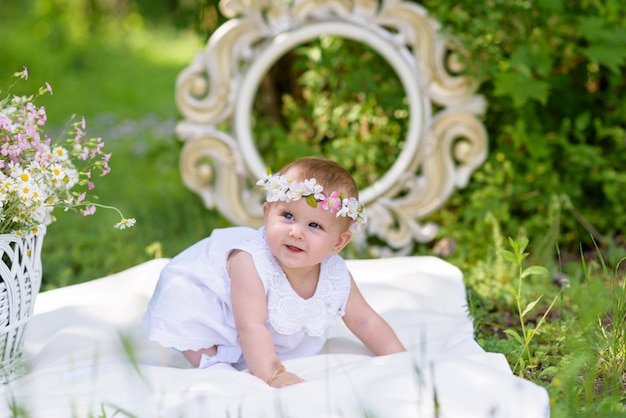 Baby girl in white dress in a spring garden with flowers