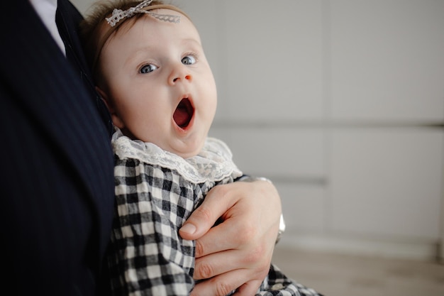 A baby girl with her mouth wide open and her mother is looking at the camera.