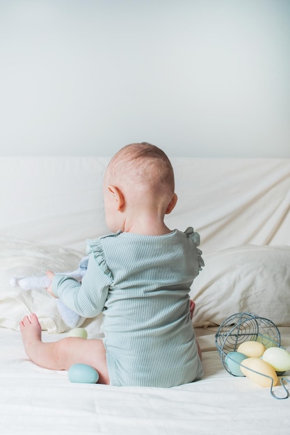 Baby girl year old on bed with basket and easter eggs egg hunting kids activity