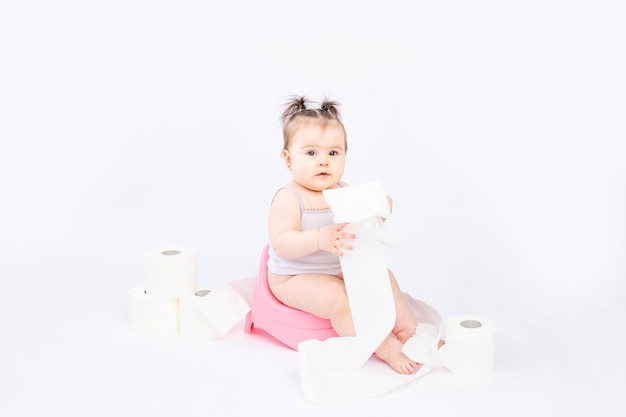 Baby on a green potty with toilet paper on a white insulated background space for text