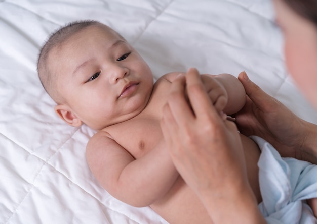 Baby hand holding finger of mother on bed