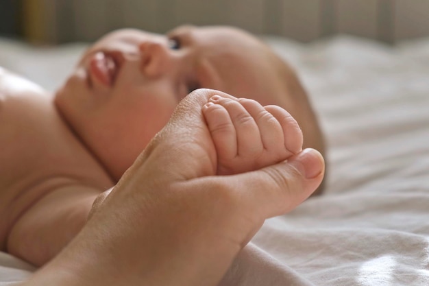 Baby hand in mother hands on her palm Happy parents holding their newborn baby tiny fingers close up Maternity family birth concept Woman touching hand of infant baby Mom and her Child