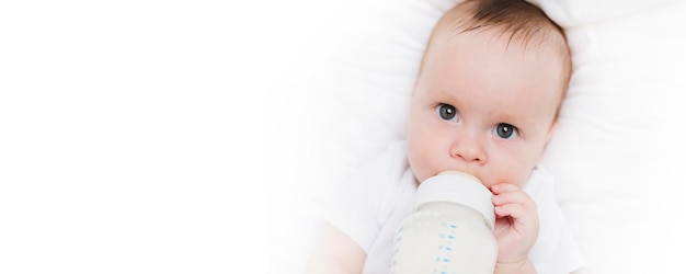 The baby in his crib eats from a bottle Baby food copyspace Artificial feeding