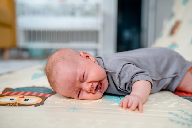 The baby is crying trying to raise head lying on his stomach