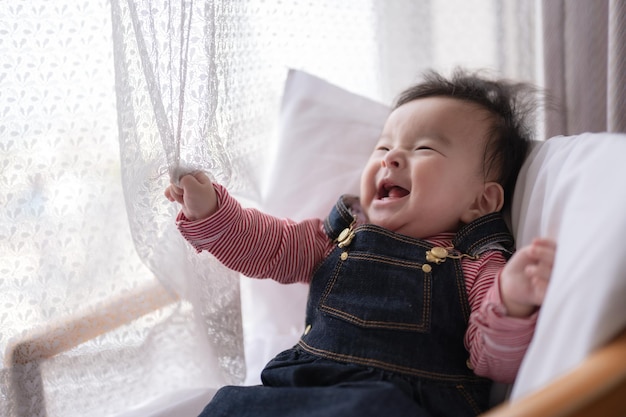 A baby is laughing and laughing in front of a window