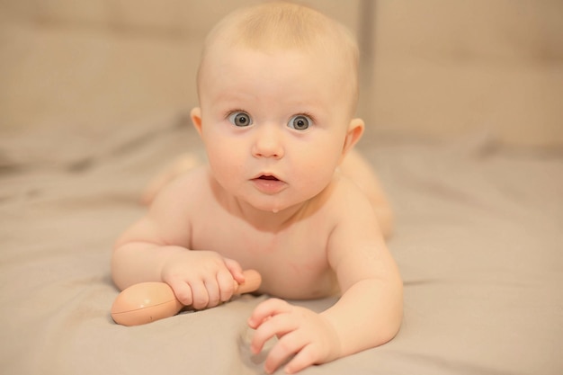 A baby is laying on a couch with a brown egg in his hand.