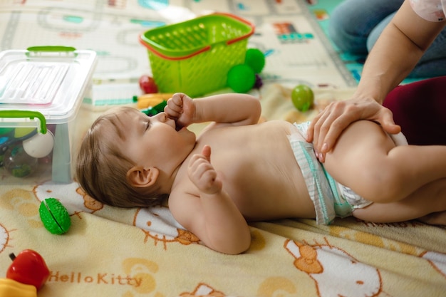 A baby is lying on a blanket with the word hello kitty on it.