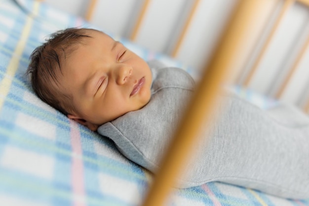 The baby is lying in a cocoon on cot He sleeps sweetly and dreams