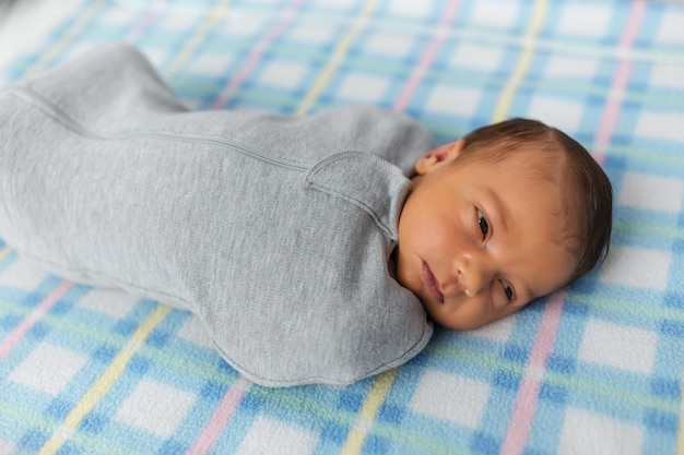 The baby is lying in a cocoon on cot He sleeps sweetly and dreams