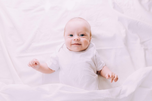 The baby is lying in his crib and looking at the camera A happy child Children's article