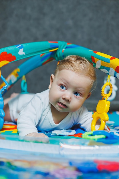 A baby is lying on a playmat The baby learns to hold his head Development of a newborn child