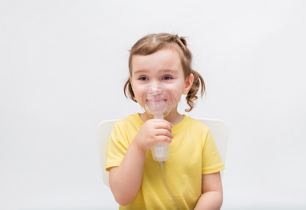 The baby is sick, the sweet girl breathes through the inhaler. Children's diseases.