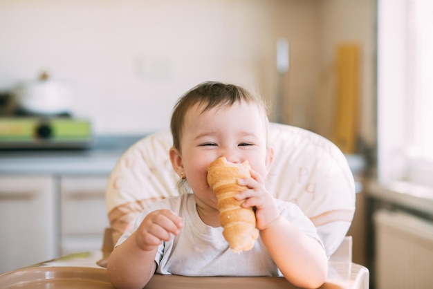 Baby in the kitchen eagerly eating the delicious cream horns, filled with a vanilla cream