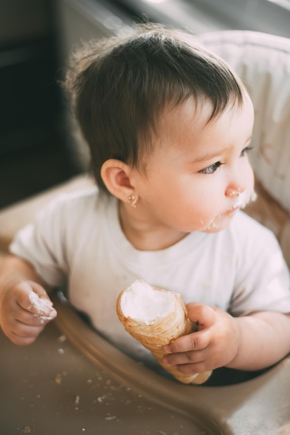 The baby in the kitchen greedily eats delicious creamy tubes filled with vanilla cream