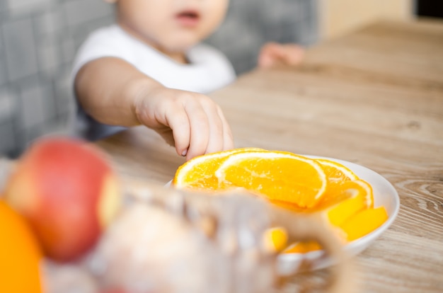 Baby the kitchen wants to take a slice of orange, trying to reach out