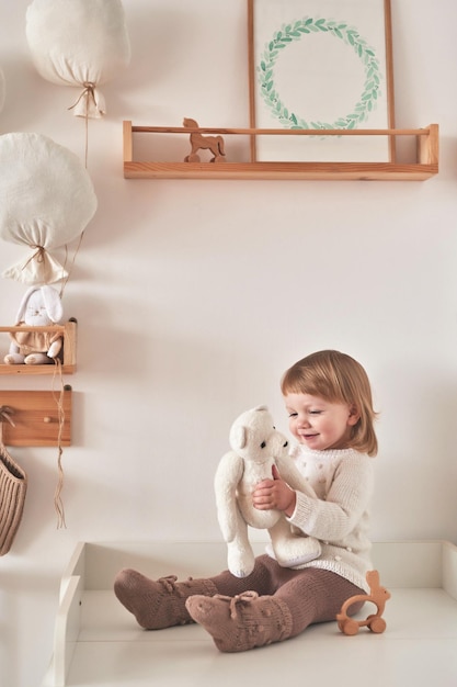 Baby in knitted clothes in children room Nursery interior