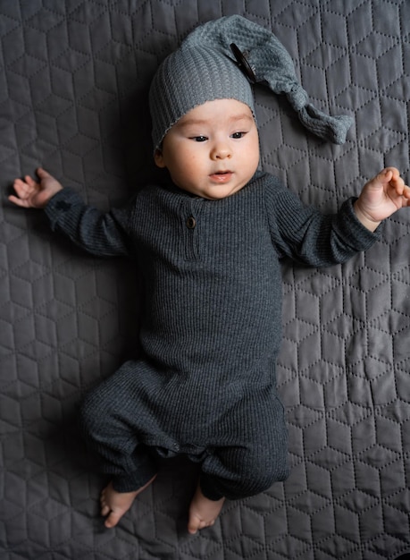 A baby laying on a bed wearing a hat