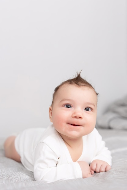 The baby lies on his stomach on the bed A beautiful baby smiles Mockup for advertising design celebration postcards