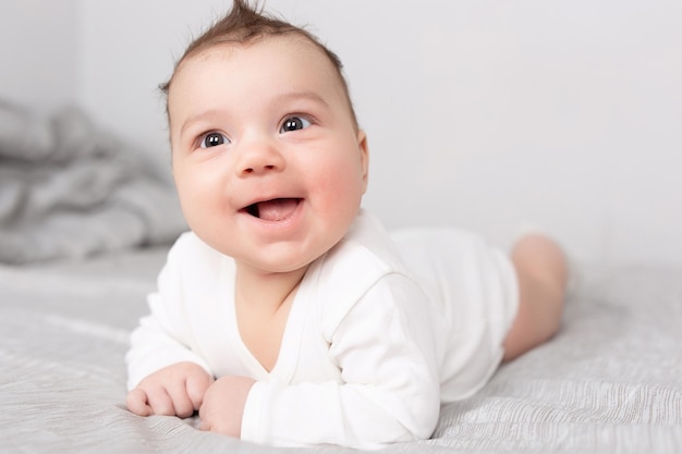 The baby lies on his stomach on the bed A beautiful baby smiles Mockup for advertising design celebration postcards