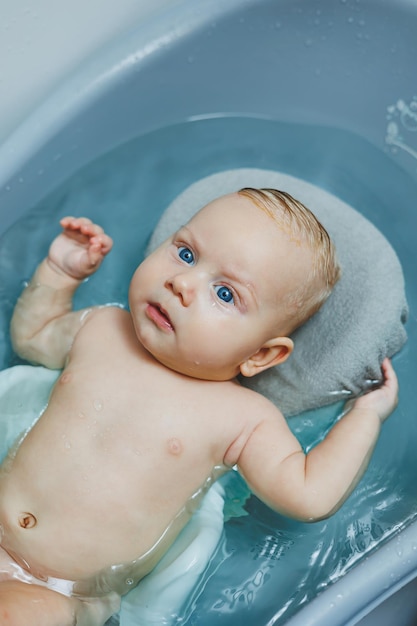 The baby lies on a stand and bathes in a bathtub Bathing a newborn baby in a bath