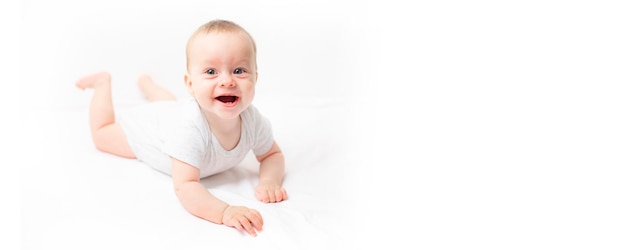 The baby lies on a white background and smiles at the camera Advertising of children's goods A child on a white background Happy baby The smile of a child Children 's article