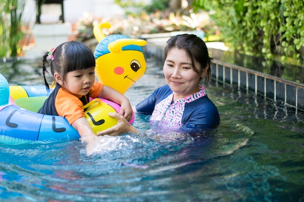 baby and mother playing water in pool