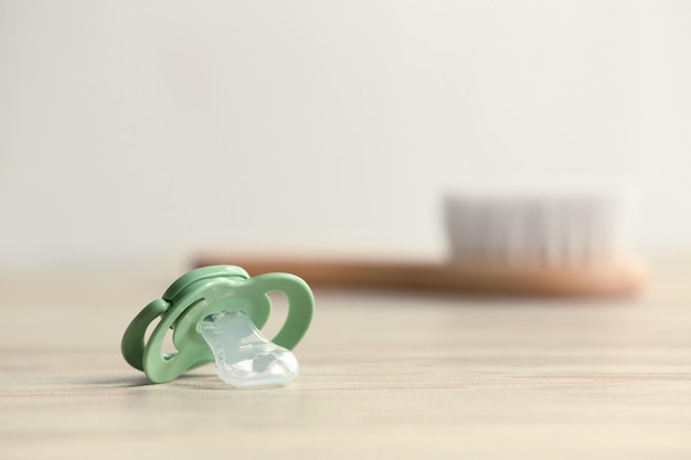 Baby pacifiers on beige table against blurred background space for text