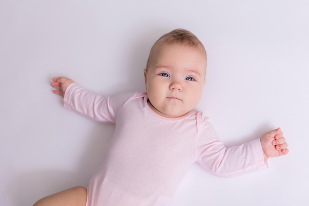 baby in a pink bodysuit is lying on the floor top view space for text High quality photo