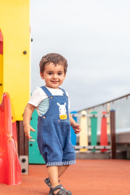 Baby playing in a playground having fun in summer park for young children