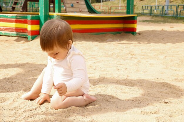 baby playing with sand on the playground