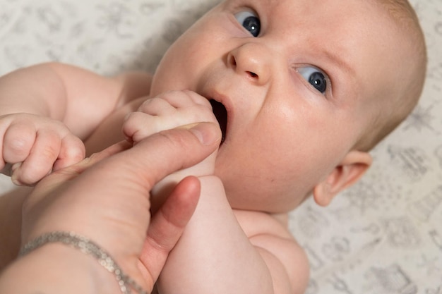 the baby plays and eats his hands and looks at the camera