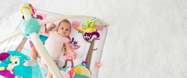 a baby plays with hanging toys on a play mat a child a baby plays at home