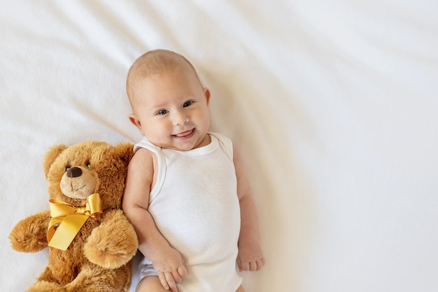 Baby plays with teddy bear against white background. 