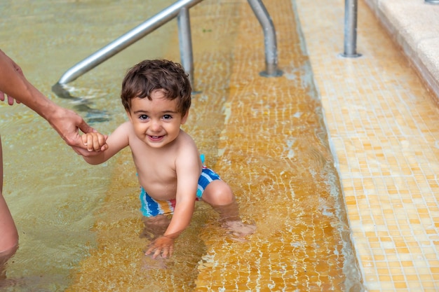 A baby in the pool enjoying the summer with his mother